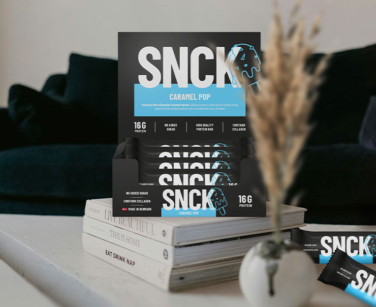 SNCK Box on a stack of books with a vase in the foreground