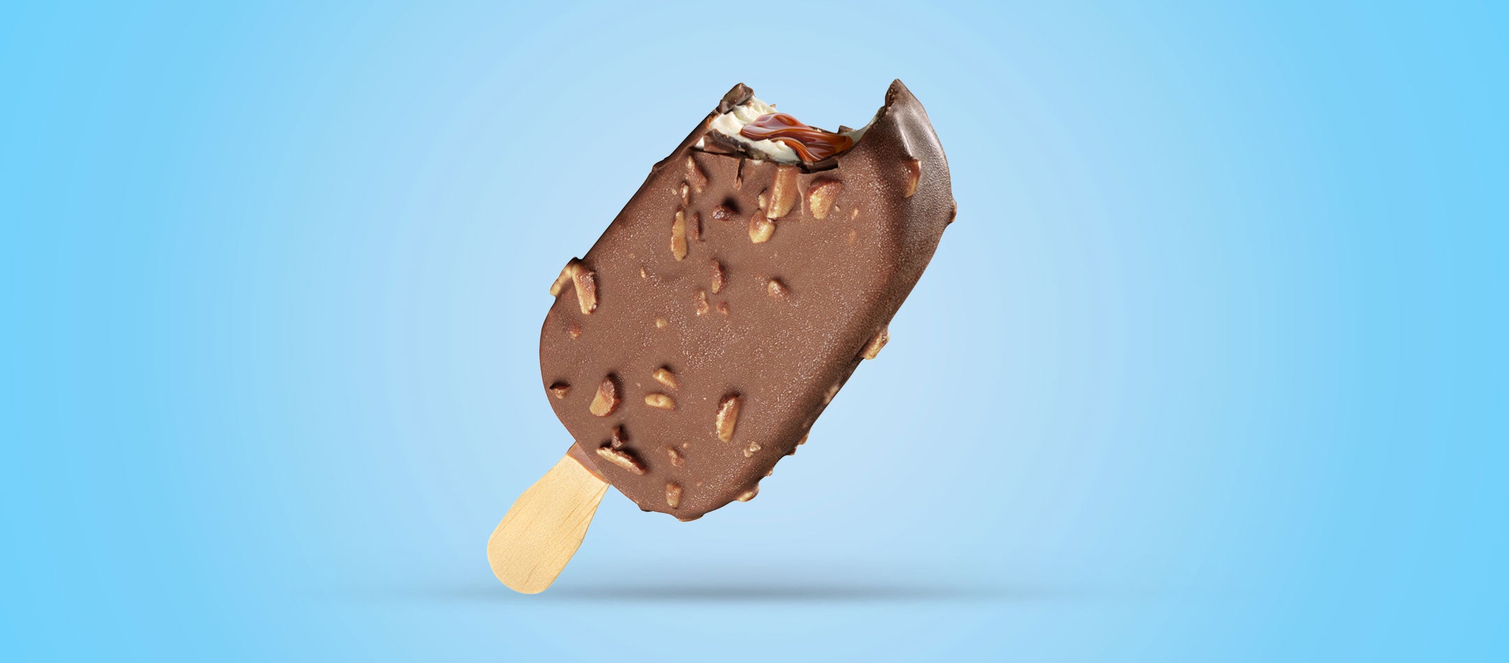 Chocolate-covered ice cream bar with nuts on a stick against a blue background
